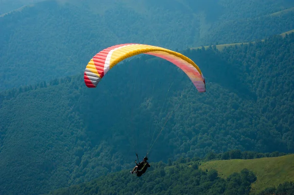 Yamaçparaşütü dağ Vadisi bir güneşli yaz gününde uçar.. 