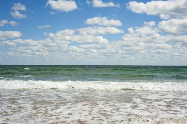 Ola de mar azul en la playa de arena. Hermosas olas marinas sobre un fondo de cielo azul con nubes en un soleado día de verano . — Foto de Stock