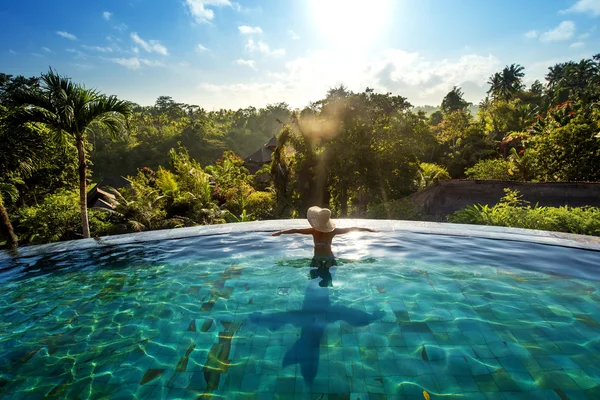 Happiness concept. Woman sunbathing in infinity swimming pool at luxurious resort — Stock Photo, Image