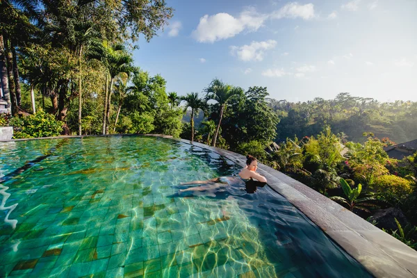 Portret van mooie vrouw in luxe resort. Jong meisje nemen van een bad en ontspannen aan infinity zwembad — Stockfoto