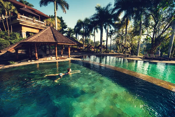 Mädchen schwimmen im Infinity-Pool im luxuriösen Resort, Hotel. Porträt einer Frau beim Schwimmen auf einer exotischen Insel — Stockfoto