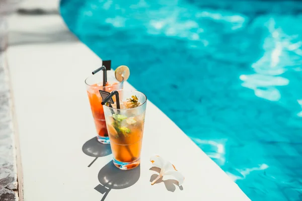Close-up of two alcoholic drinks, ice and gin and tonic lemonade and mojito with lime served cold at pool bar — Stock Photo, Image