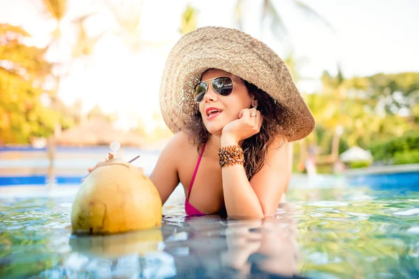 Сексуальна жінка насолоджується кокосовим коктейлем у басейні, добре проводячи час у воді — стокове фото