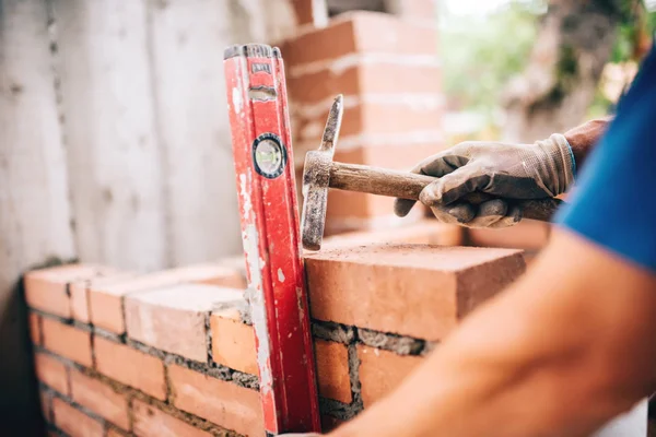 Industriële werknemers bouwen van buitenmuren, met behulp van hamer en niveau voor bakstenen in cement te leggen. Detail van de werknemer met hulpmiddelen — Stockfoto