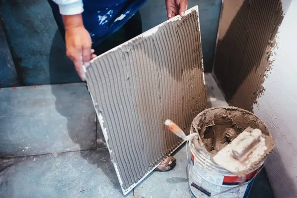 Industriële werknemer installeren badkamer keramische tegels van de vloer, het toevoegen van flexibele cement lijm met kam Troffel — Stockfoto