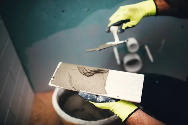 Industrial close up detail of worker adding cement adhesive on small ceramic tiles — Stock Photo, Image