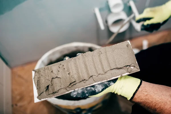 Muratore applicando malta su piastrelle di ceramica e lavorando sulla ricostruzione di un bagno — Foto Stock