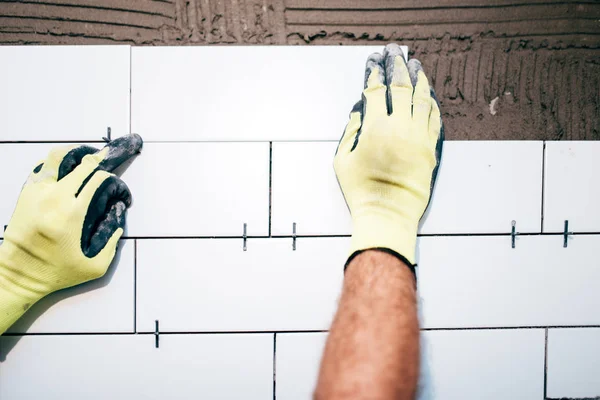 Průmyslové dělníky ruce instalaci keramických dlaždic na vnitřní zdi, údržbář pomocí plastových distancer pro úpravu obkladů. Stavební detaily — Stock fotografie