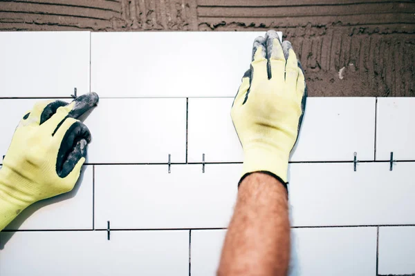 Manos de los trabajadores industriales que instalan baldosas de cerámica en las paredes interiores, manitas utilizando distanciador de plástico para ajustar las baldosas. Detalles de construcción —  Fotos de Stock