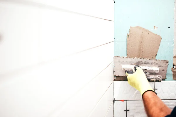 Renovação em andamento, detalhes da construção, close-up das mãos do trabalhador usando espátula e adição de adesivo — Fotografia de Stock