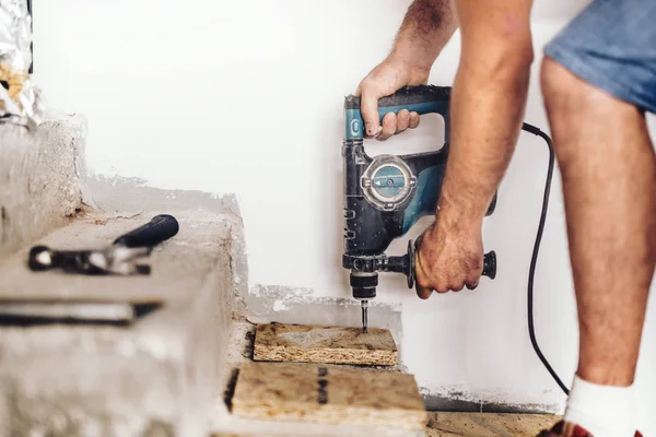 Промышленные строители сверлят отверстия в деревянной доске и бетоне с помощью профессионального оборудования — стоковое фото