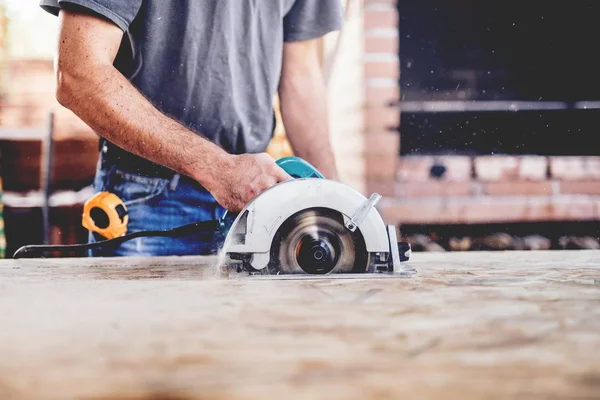 Bouwvakker, industrieel timmerman met circulair verstekzaag voor snijplanken — Stockfoto