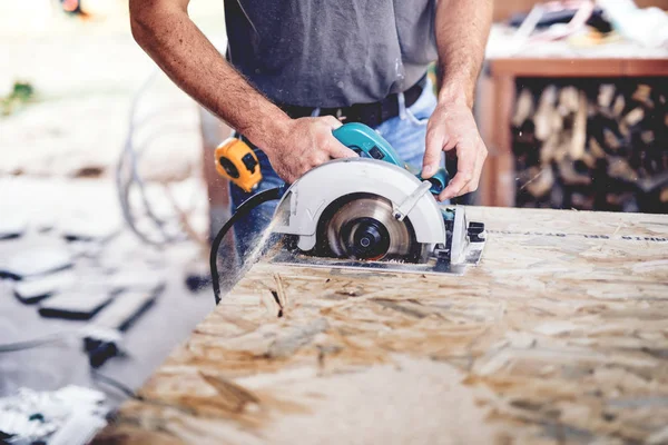 Construction man working with a chop saw in wood workshop. Details of wood cutting using circular sa — Stock Photo, Image