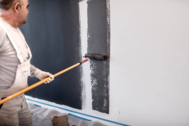 Orta iç beyaz duvarlar üzerinde çalışma boya silindiri ile çalışan adam yaşlı. Dekorasyon inşaat ressam