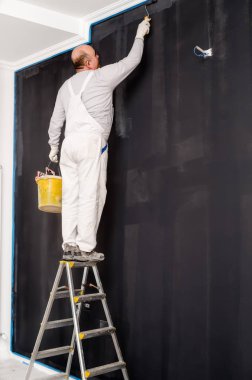 boya silindiri kullanarak ve gri duvarlar boya yetişkin adam portresi. Yenileme ayrıntıları