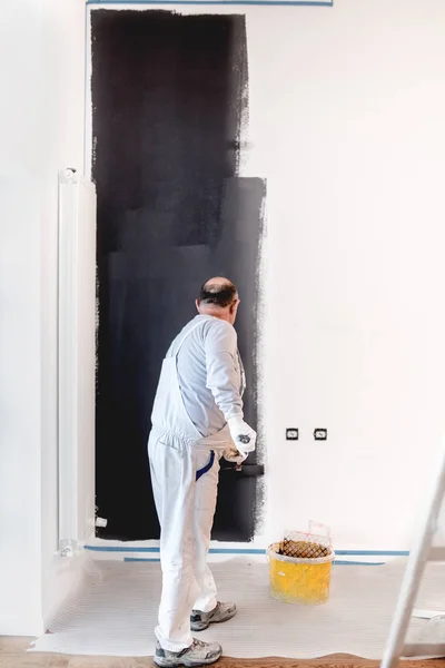 Pintor de mão homem no trabalho com um rolo de pintura, balde e outras ferramentas profissionais. Casa pintor usando tinta cinza — Fotografia de Stock