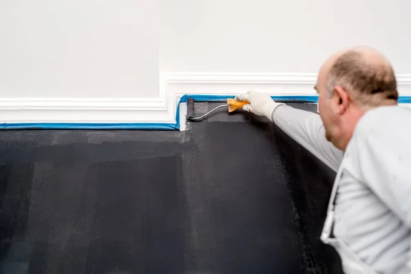 Homem útil fechar detalhes de pintar uma parede cinza usando paintroller. Paredes de pintura de trabalhador de construção — Fotografia de Stock