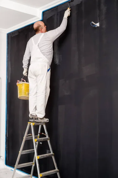 Retrato do homem crescido usando rolo de pintura e pintura paredes cinzentas. Detalhes da renovação — Fotografia de Stock