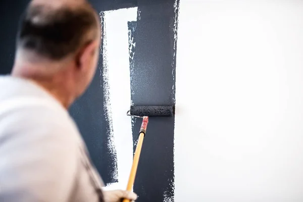 Homem de meia idade industrial que trabalha com rolo de pintura em obras de renovação — Fotografia de Stock