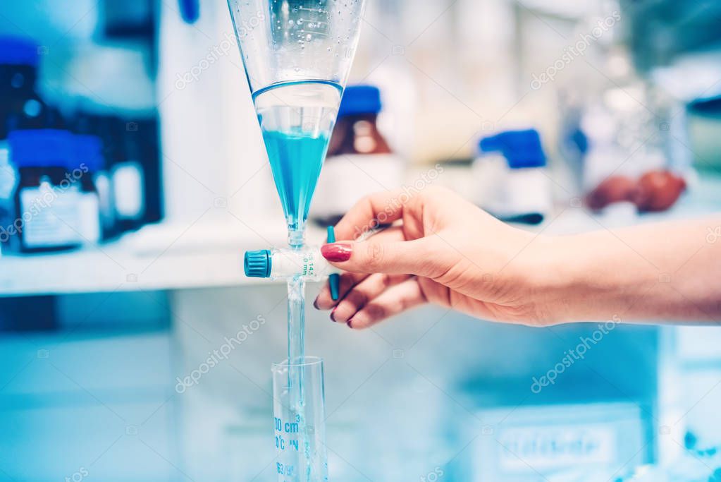 Scientist working in laboratory, pouring liquid substances and testing chemical reaction 