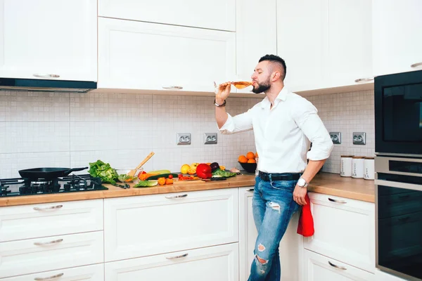 Cool male, handsome guy drinking wine and preparing dinner