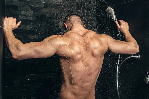 Muscular culturista fitness tomar una ducha después del entrenamiento. Cerrar detalles de los músculos de la espalda en la ducha — Foto de Stock