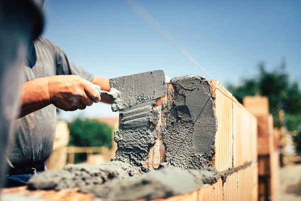 Bricklayer construction worker installing brick masonry on exterior wall with trowel putty knife — Stock Photo, Image