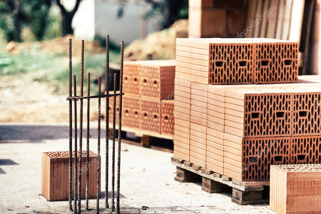 Industrial construction site, reinforcement of steel bars, wooden boards and brick stacks