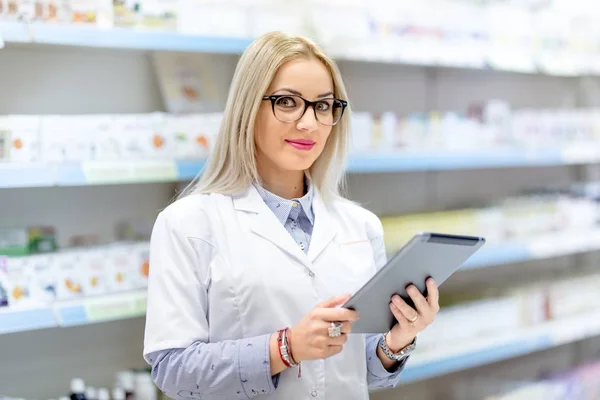 Lindo médico rubio en uniforme blanco usando tableta y tecnología en el campo farmacéutico o médico — Foto de Stock