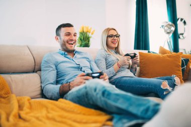 Eğleniyor ve modern oturma odasında video oyunları oynarken gülüyor genç Çift