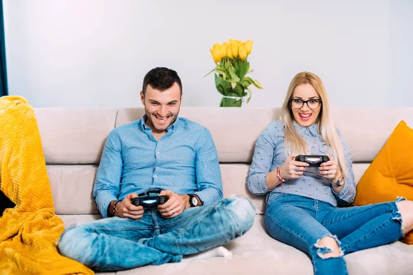 Glückliches Paar, das digitale Videospiele mit Joystick-Controller spielt, während es auf dem Sofa oder der Couch sitzt. moderne Details digitaler Technologie — Stockfoto