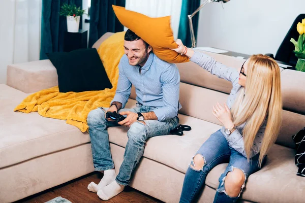 Νεαρό ζευγάρι έχει τη διασκέδαση στο apartament, ελκυστικό ζευγάρι που ασχολούνται με ένα μαξιλάρι μάχη κατά τη διάρκεια της online παιχνίδια διαφορά — Φωτογραφία Αρχείου