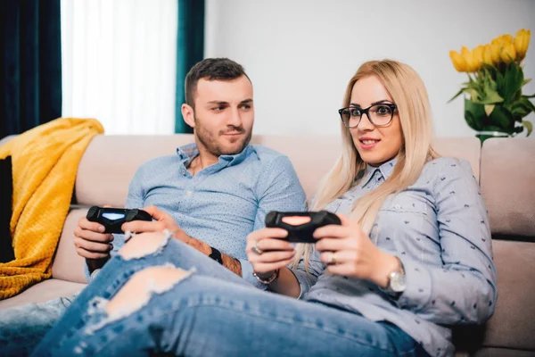 Mann und blonde Frau spielen Videospiele. Der Mann ist wütend und das Mädchen gewinnt. Details des modernen Lebensstils und Freizeitkonzepts — Stockfoto