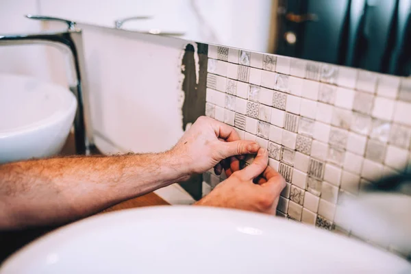 Detalhes de perto do trabalhador industrial aplicando azulejos padrão de cerâmica em mosaico no chuveiro do banheiro são — Fotografia de Stock