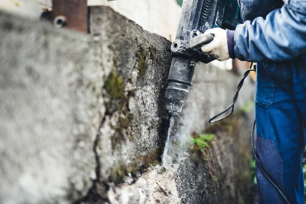 Werknemer met behulp van industriële bouw hulpmiddel, industriële jackhammer met sloop puin en cemen — Stockfoto