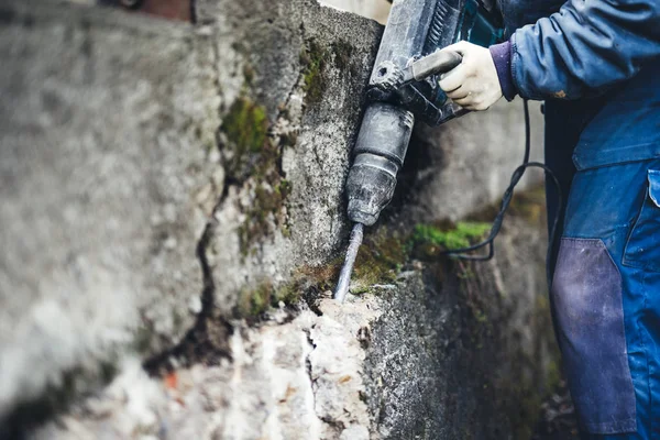 Mężczyzna robotnik wywiercić w ścianie za pomocą jackhammer. profesjonalny pracownik w budowie — Zdjęcie stockowe