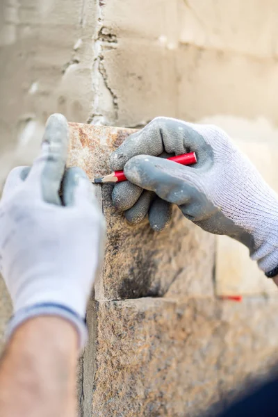 Détails des mains des travailleurs prenant des notes et dessinant sur la pierre. Ouvrier de la construction pavage façade de la maison avec pierre — Photo