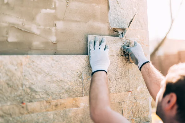 Mason pracownik instalacji płytek kamiennych na ścianie na placu budowy — Zdjęcie stockowe
