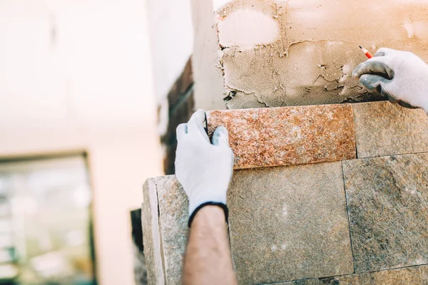 Εργαζόμενος εγκατάσταση κεραμιδιών πετρών στο εργοτάξιο. Τοιχοποιία λεπτομέρειες στον εξωτερικό τοίχο με μυστρί στόκος knif — Φωτογραφία Αρχείου