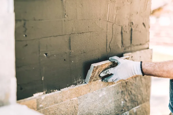 Ouvrier de la construction maçon plaçant étroitement tuile de pierre sur le mur vertical. Détails de l'industrie - chantier — Photo