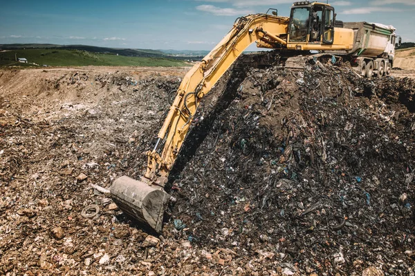 Industrial machinery excavating garbage. Close up of heavy duty excavator using scoop and working