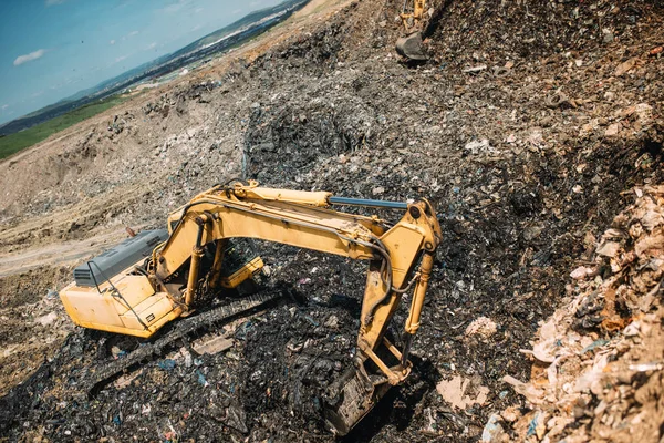 city waste on dumping grounds. Details of industrial excavators working, digging and loading