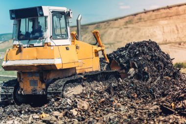 Çöp iterek ve çöp sitesinde çalışan endüstriyel buldozer