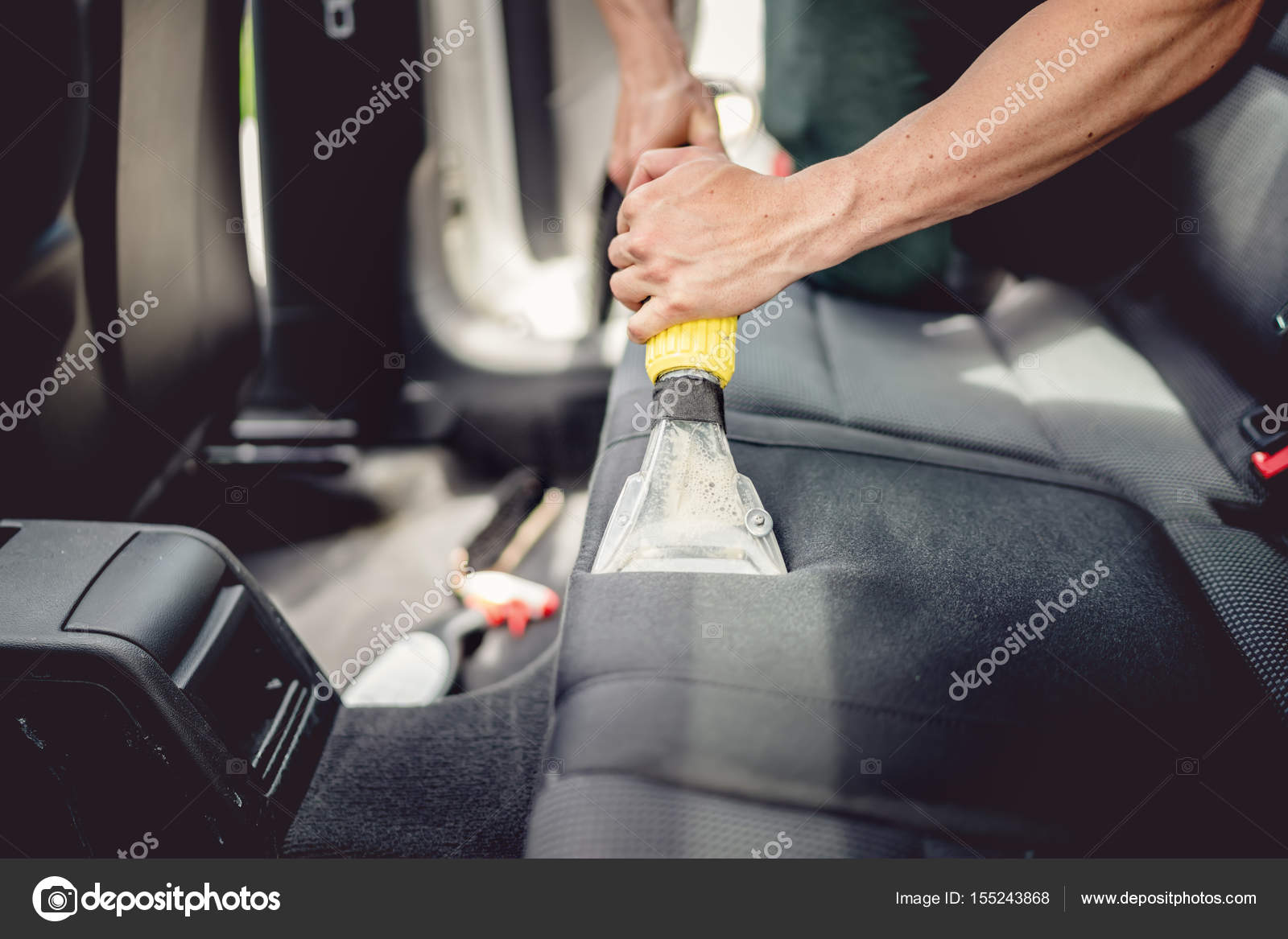 Professional detailer vacuuming carpet of car interior, using steam vacuum  Stock Photo by ©bogdan.hoda 155243992