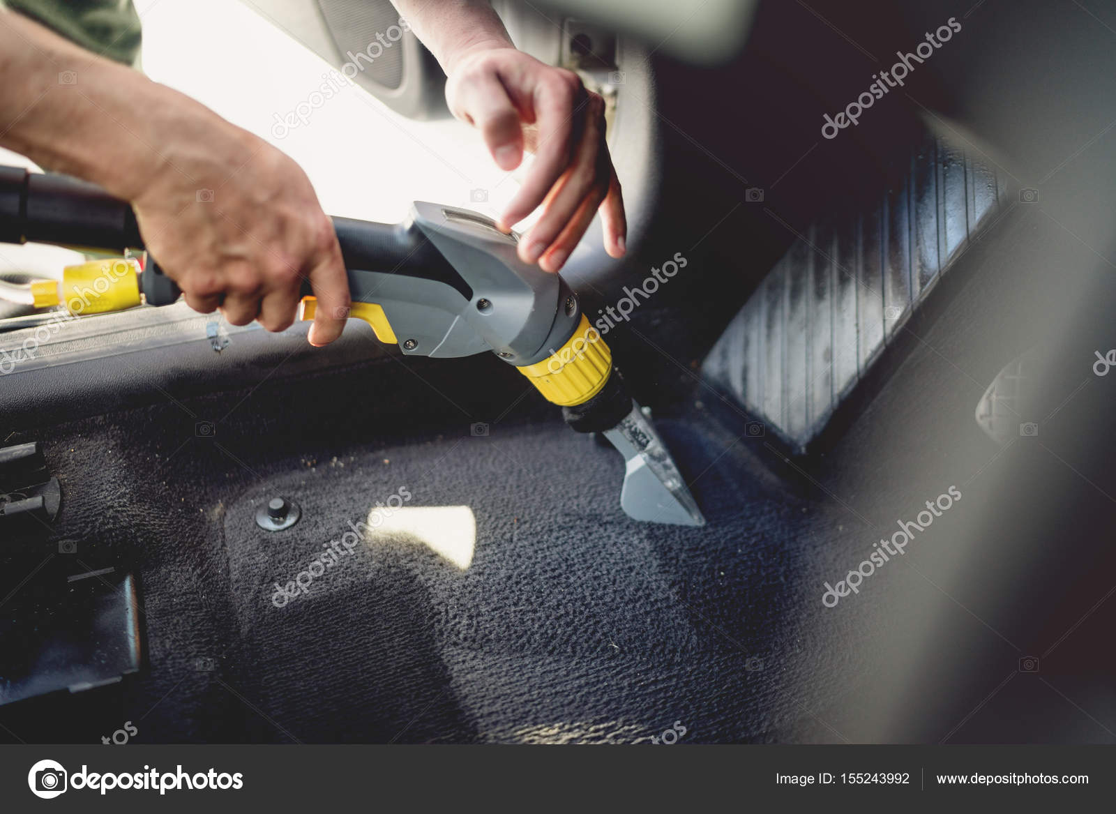 Professional detailer vacuuming carpet of car interior, using steam vacuum  Stock Photo by ©bogdan.hoda 155243992
