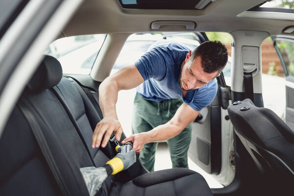 Professional worker vacuuming and cleaning automobile. Car care and detailing concept