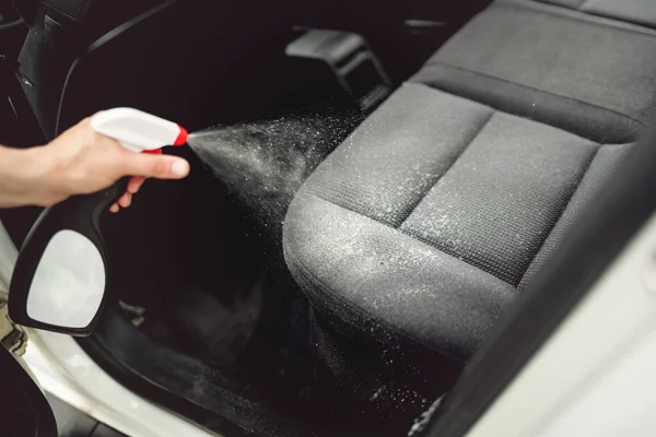 Concept d'entretien de voiture, détaillant et nettoyer les intérieurs de voiture. Solution de nettoyage de pulvérisation de travailleur sur le revêtement de voiture — Photo