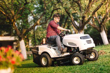 Professional gardner using lawn mower and cutting grass clipart