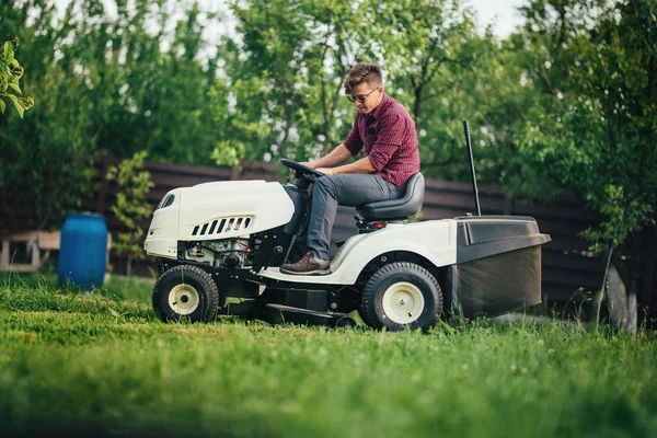 Travailleur utilisant tondeuse à gazon pour couper l'herbe dans le jardin — Photo