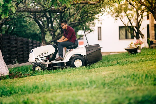 Чоловік працює в саду, розслабляючий день у вихідні та стриже траву з газонокосаркою — стокове фото